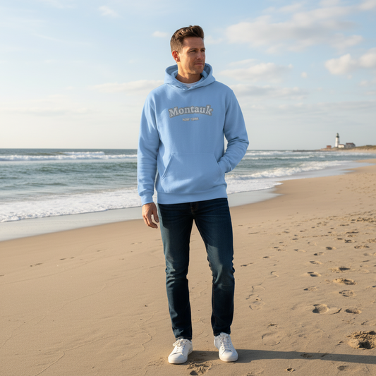 Man wearing a light blue hoodie with 'Montauk' text on a beach