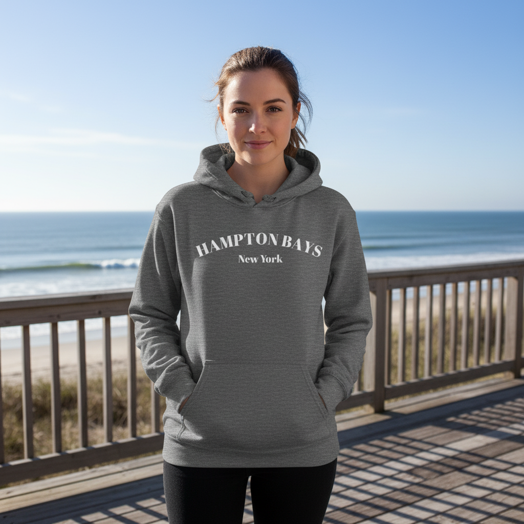 Hampton Bays Hoodie in heather gray worn by woman on boardwalk, cozy unisex beach sweatshirt ideal for cool coastal evenings.