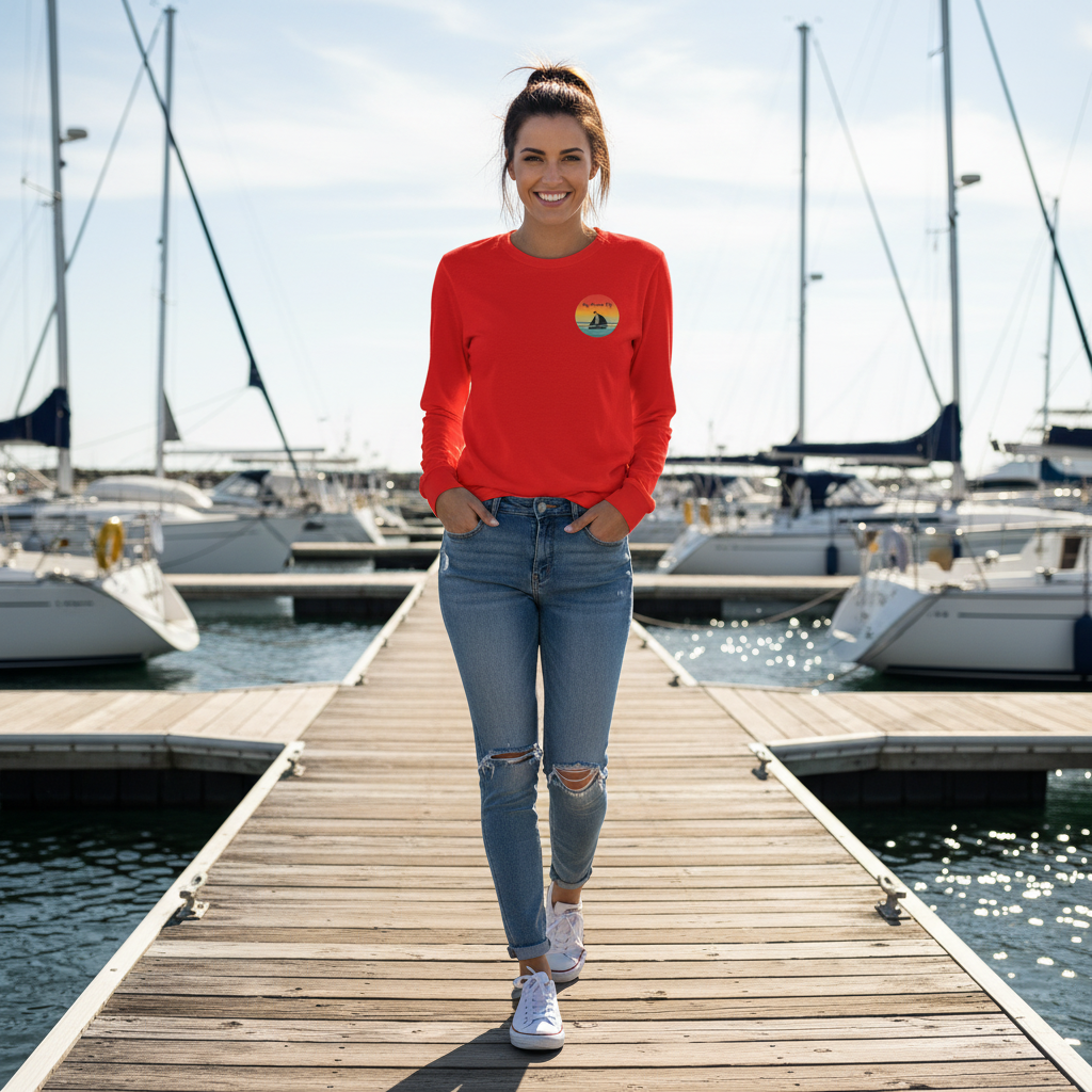 Woman in a red sweatshirt and blue jeans standing on a dock with boats in the background
