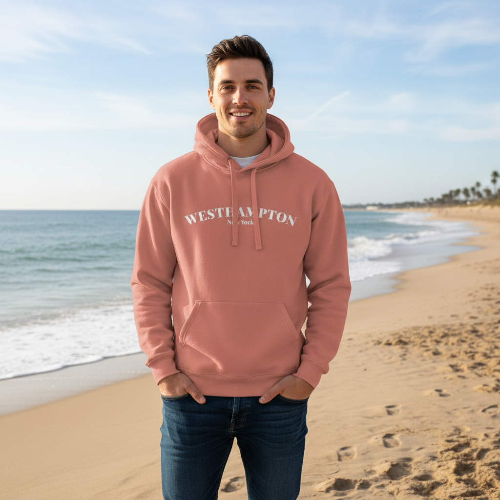 Man wearing a pink hoodie with 'Westhampton' text on a beach